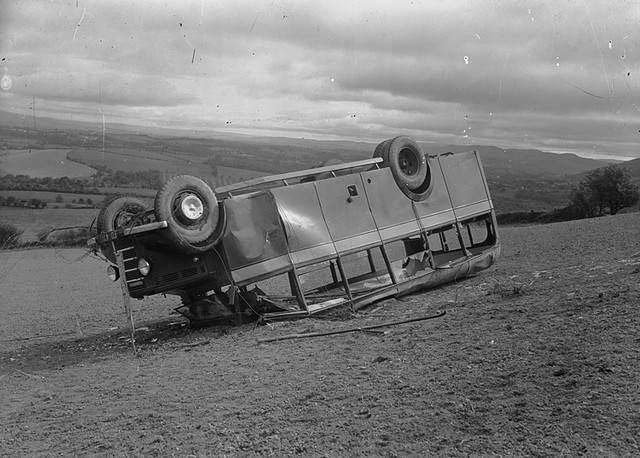 Image of a Bedford bus on its roof in a field - ‘Coach accident’ from the P B Abery Collection at the National Library of Wales
