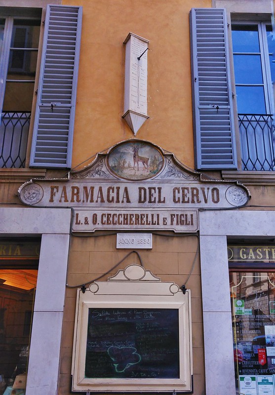 Decorative sign reads 'Farmacia del Cervo: L&O Ceccerelli e Figli' in Italian (translation: pharmacy) 