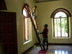 Two people painting a window's trim.