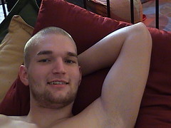 A man lounging shirtless on a couch.