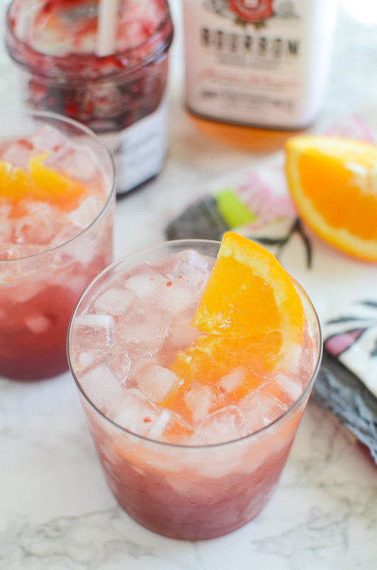 Raspberry Bourbon Smash - your new favorite cocktail! Raspberry jam, orange juice, bourbon, and orange liqueur smashed together and served over ice. 