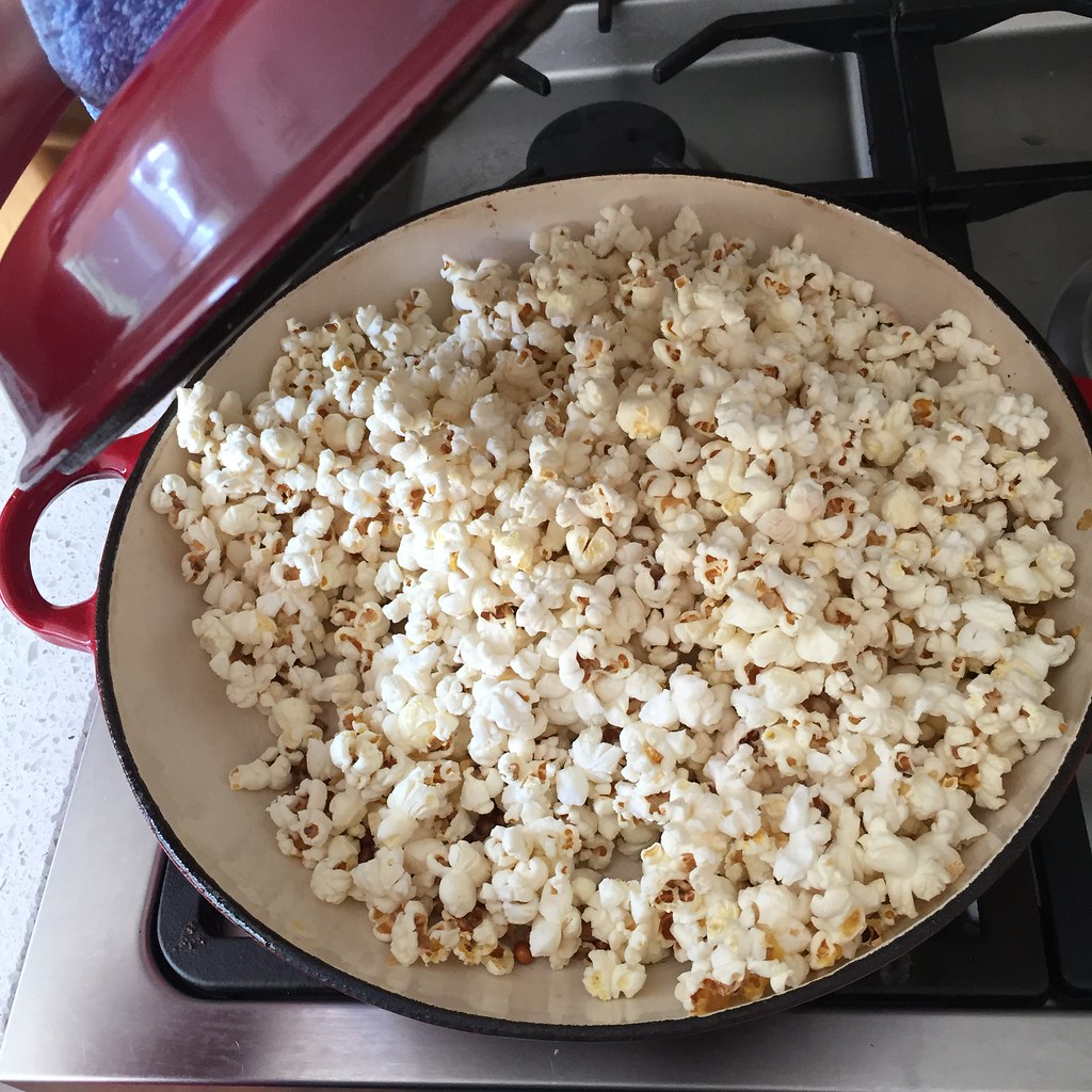 popcorn cooked on the stove in a red cast iron pan