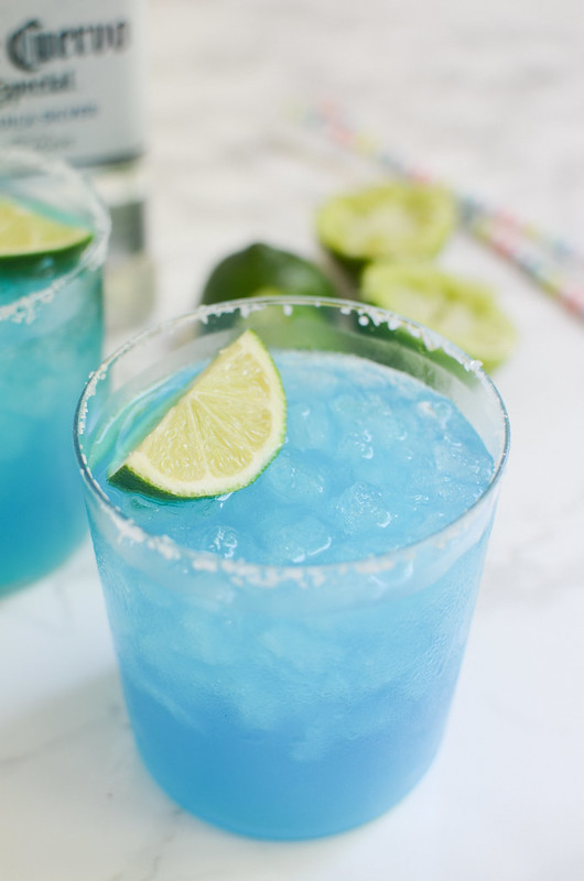 Blue Margaritas in a salt rimmed glass with a lime wedge