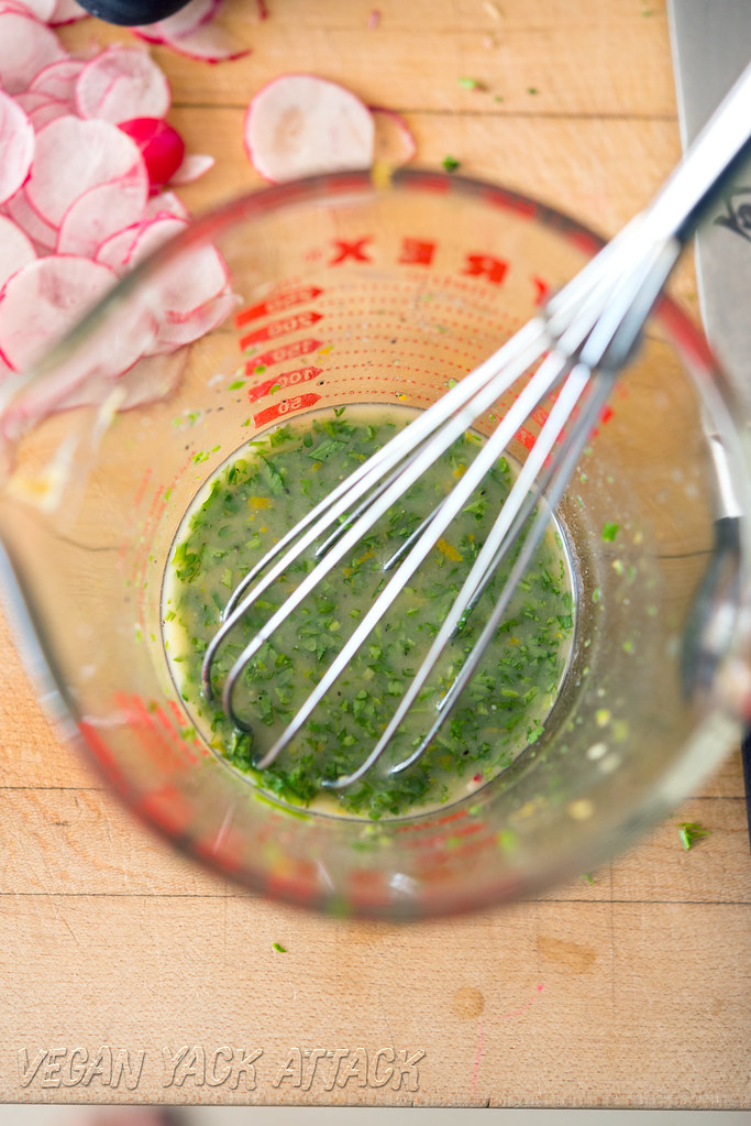 Image if herb dressing in a liquid measuring cup with whisk