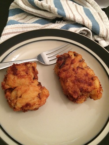 Two lumps of fried mac and cheese on a plate with a fork.