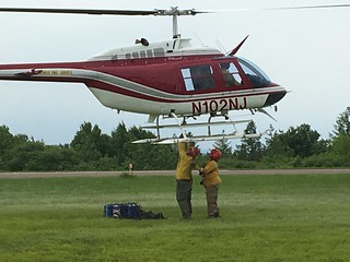 Two wildland firefighters securing supply load to bottom of helicopter