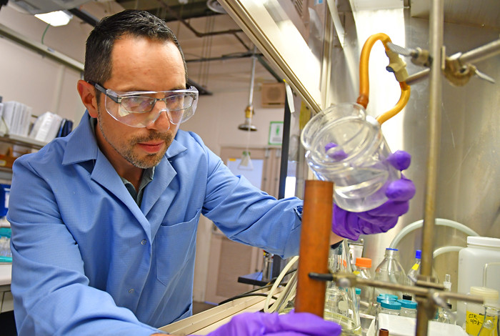 Man in laboratory pouring liquid into beaker.