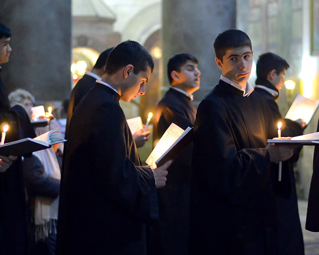 Sacerdotes orando con velas en las manos en la iglesia del Santo Sepulcro de Jerusalén