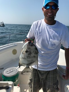 Photo of Man holding a spadefish on his boat