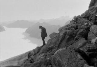 John Robert Murrell, taking a photograph from the summit ridge of Mount Elliot above the Jervois Glacier, showing the north branch of the Clinton River valley filled with fog
