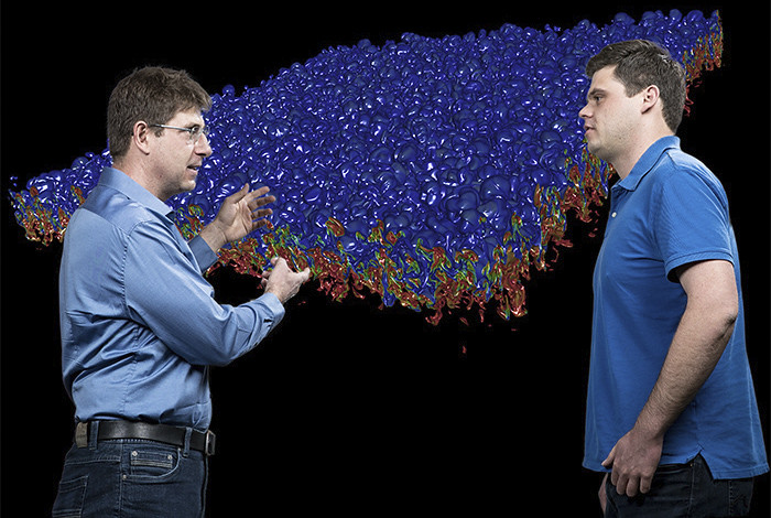 Photo of Daniel Livescu and Jon Baltzer standing in front of computer modeling picture
