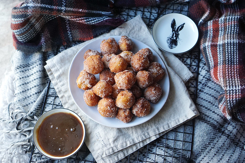 Plate of gluten free churro donut holes rolled in cinnamon sugar with a homemade caramel dipping sauce. | Featuring H&M Home small rabbit plate.