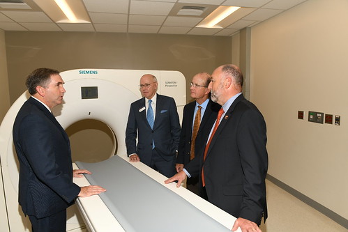 Auburn University and Gulf Shores officials stand next to a CT scanner machine.