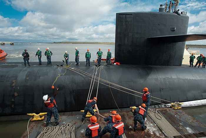 Men securing a submarine that has returned to a dock.