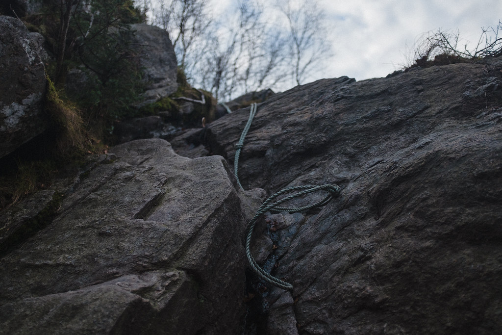 rope hanging down a cliff to help people get up a steep stretch on a hiking trail.