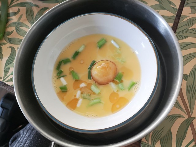 pre cooked whisked eggs with a salted duck egg and spring onions in a dish in a steamer