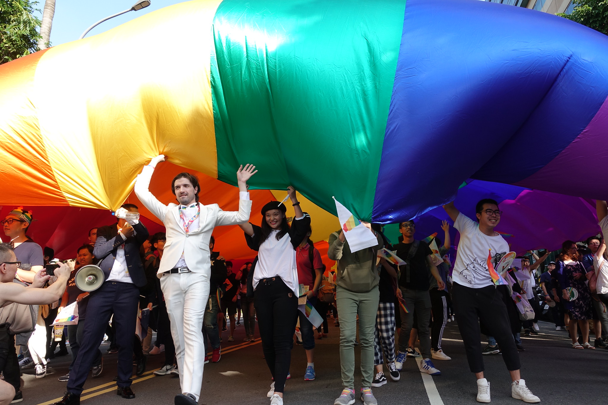 眾人一同舉起遊行中的大面彩虹旗。（攝影：張智琦）