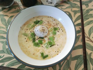 dish with a bue rim and a visible egg with spring onions and black oeooer 