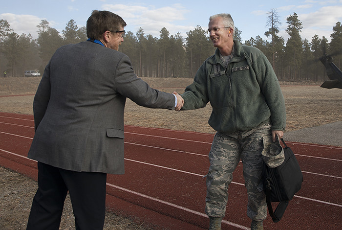 Two men standing outdoors shaking hands.