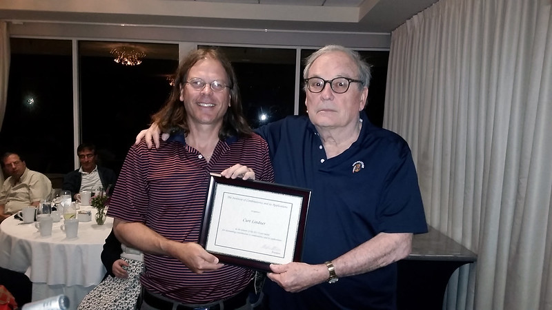 Curt Lindner with son Curt holding the Euler Medal certificate in a conference room at the 48th Southeastern International Conference on Combinatorics, Graph Theory and Computing