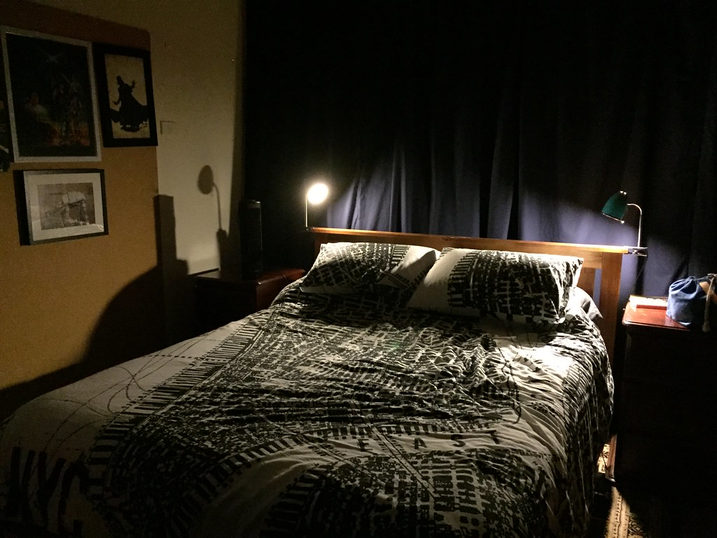 our bedroom: lit by lamplight on either side of the bed with a blue curtain behind