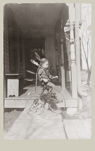 Playing in a head dress on a tricycle.