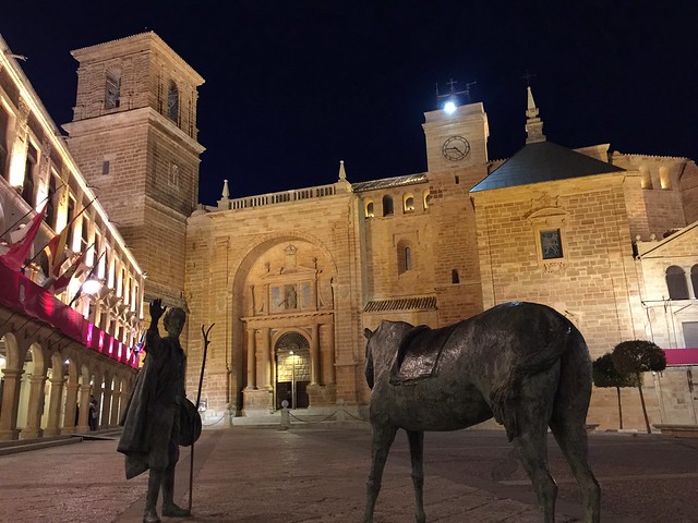 Fotografía nocturna de la Plaza Mayor de Villanueva de los Infantes con su conjunto escultórico de Don Quijote y Sancho Panza
