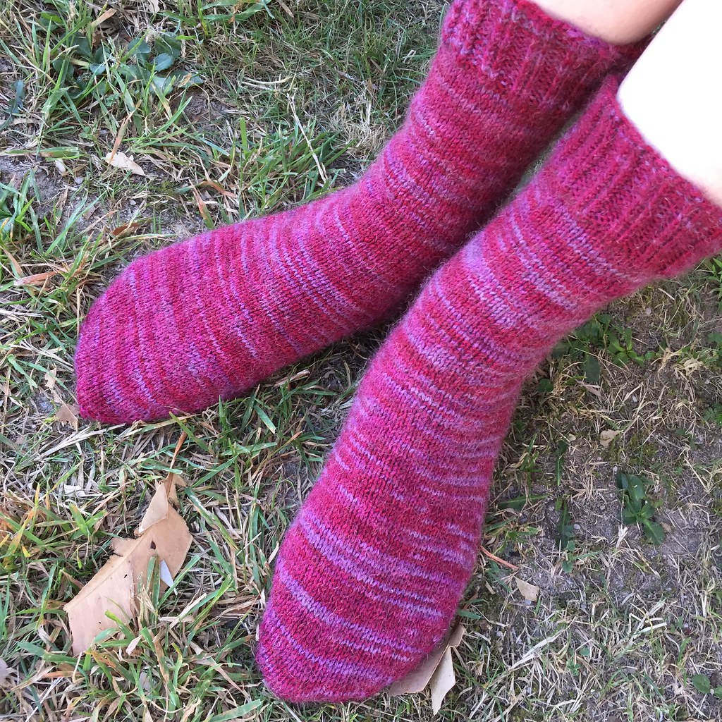 a pair of jo torr's vanilla sock with gusset heel and eye of partridge heel flap in naturally waikiwi prints yarn in a red/pink colourway