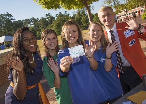 A table of students waves hello on Hey Day while holding a name tag for Aubie.