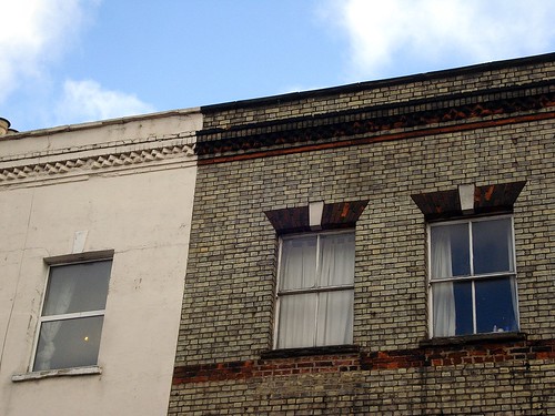 The upper floors of a terraced building showing three windows.