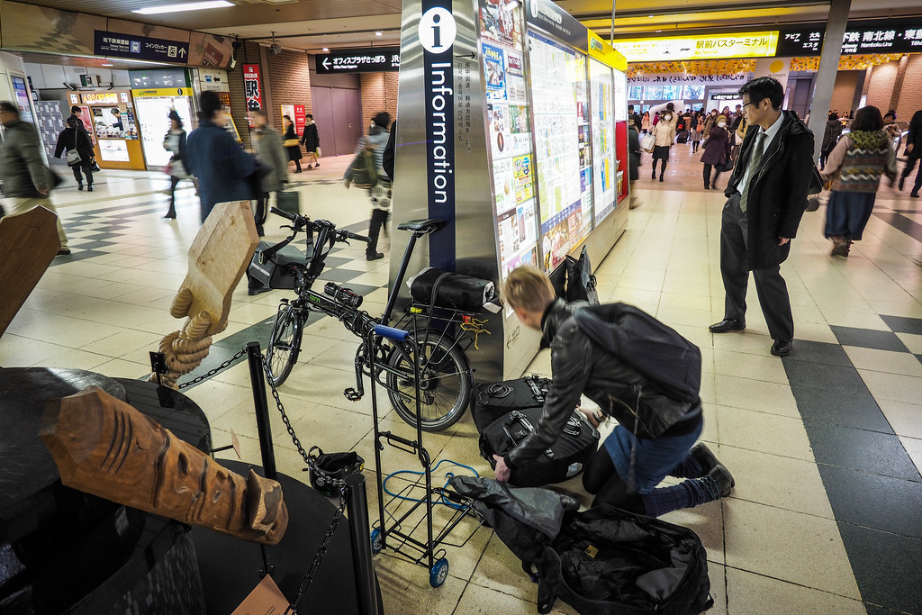 Packing up a Tern folding bicycle for train travel in Sapporo station, Japan