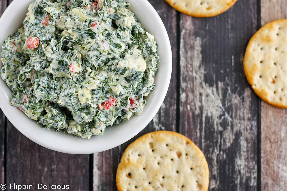 Creamy gluten-free skinny spinach artichoke dip made with greek yogurt. Packed full of veggies and protein, and less guilt when you eat it all.