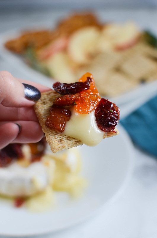 Bacon Cranberry Baked Brie - the perfect holiday appetizer! Brie topped with bacon, dried cranberries, apricot preserves, fresh rosemary and then baked until melty and delicious! Serve with crackers or apple slices at your next holiday party!