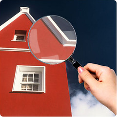 A home with a magnifying glass held up to it.