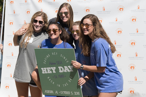 Five female students pose in a photo booth holding a Hey Day sign.