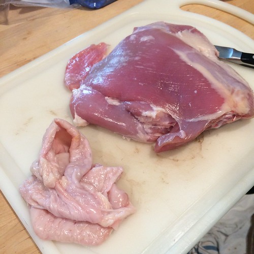 A skinned turkey thigh with the skin next to it.