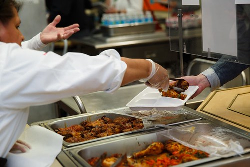 Food service staff serving barbeque chicken to students