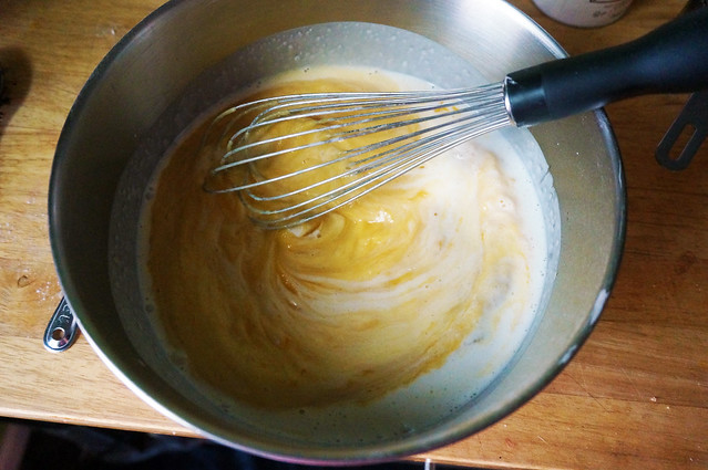 Pumpkin puree and coconut milk, swirled together by a whisk in a large stainless steel mixing bowl