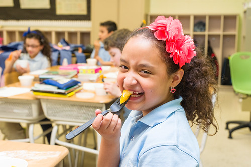 An elementary school student in West New York, New Jersey, enjoying a farm fresh bite of yellow tomato