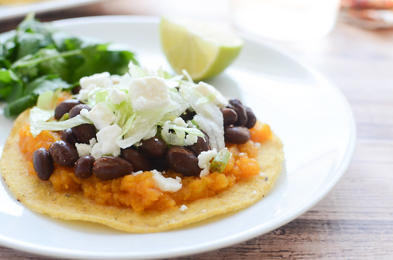 Butternut Squash and Black Bean Tostadas - black beans seasoned with chili powder and lime juice on top of butternut squash and crunchy tostadas. Topped with queso fresco and crisp lettuce. Perfect for meatless Monday!
