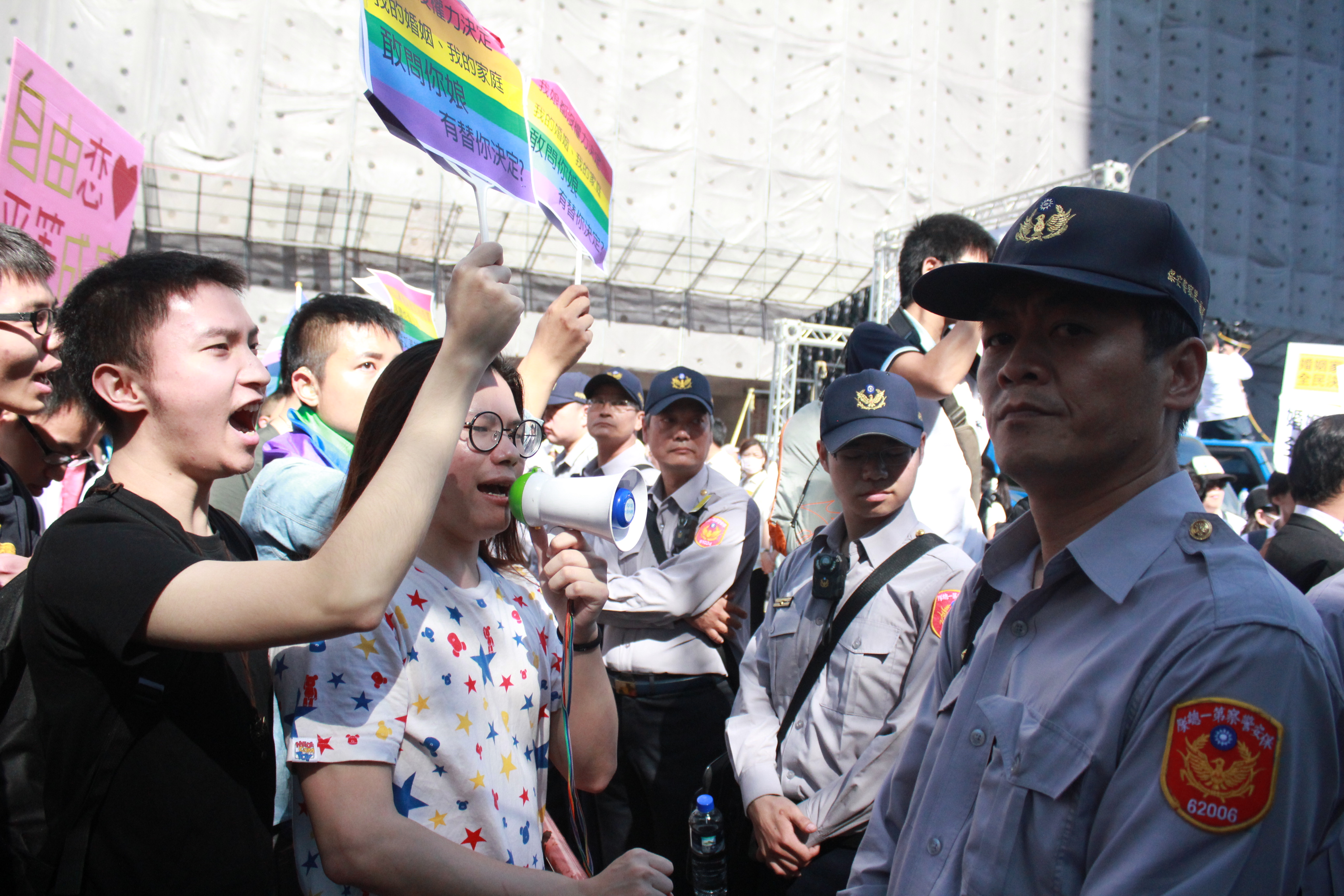 在濟南路反同婚現場，隔著警察，有大學性別社團和支持同婚的青年與下福盟對嗆。（攝影：張宗坤）