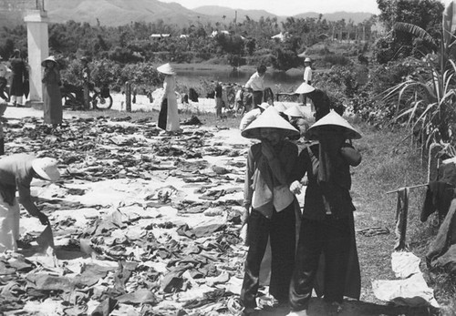 Weeping Women -- Two grieving women walk through a school yard where remains of 250 victims found in a mass grave near Hue were spread for identification