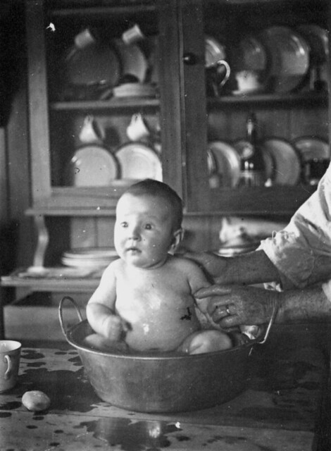 Baby being bathed on the kitchen table, ca. 1918