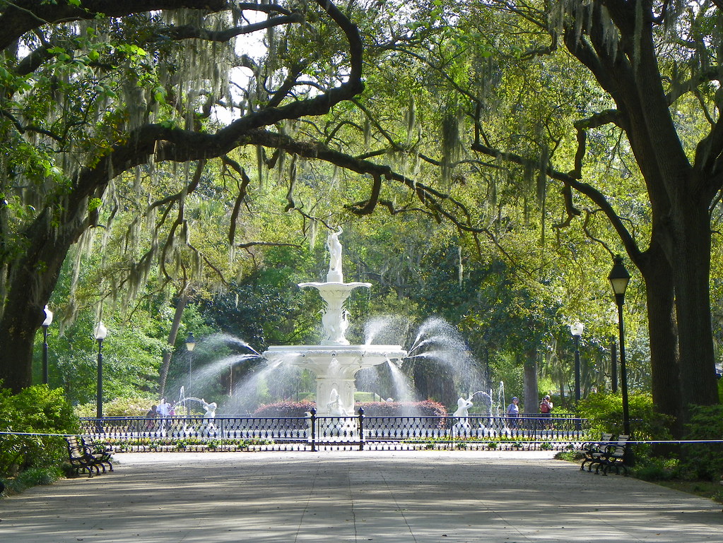 A park with a fountain in the middle and green trees  in Savannah, Georgia.