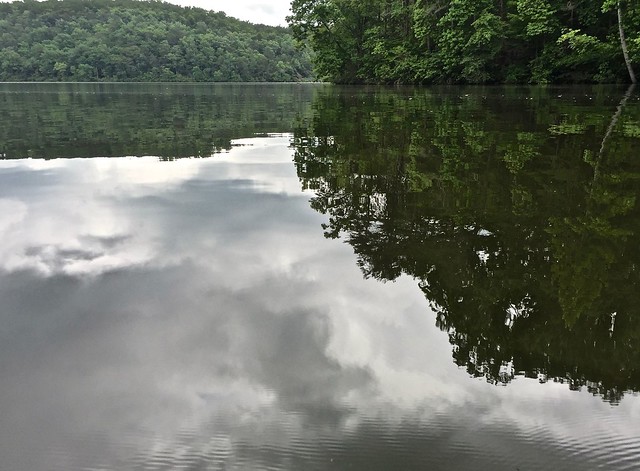 A view of the glassy lake with the dam nearly hidden in the background at Holliday Lake State Park in Virginia