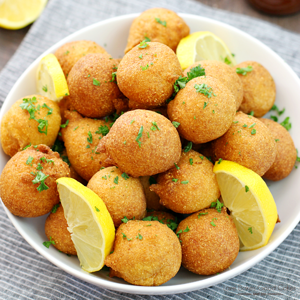 Classic Hush-puppies in a white bowl with slices of lemon.