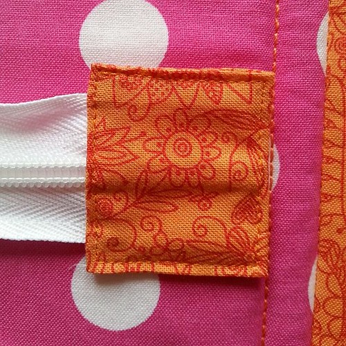 After tips from @quirkygranolagirl and @jeifner, I used fabric glue to fix the zip tab before stitching it and I'm really pleased with how well it's turned out.  Thanks for the tips!