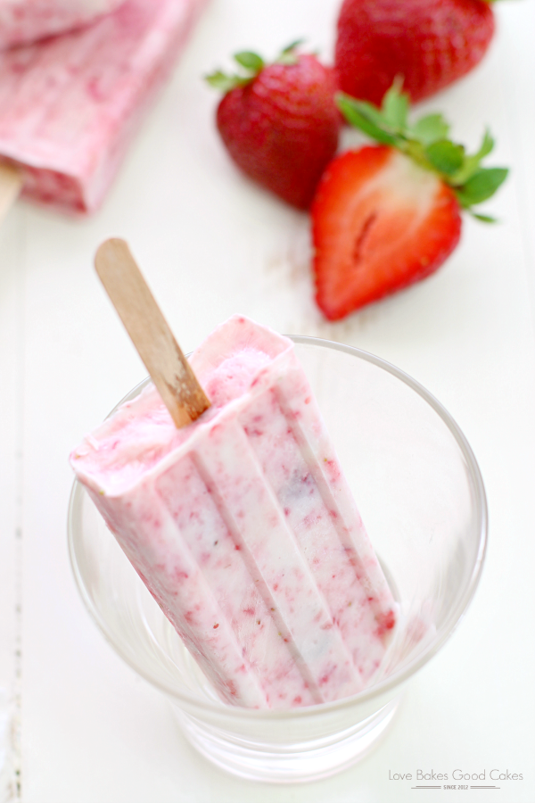 Strawberry-Yogurt Popsicle inside a glass with fresh strawberries.