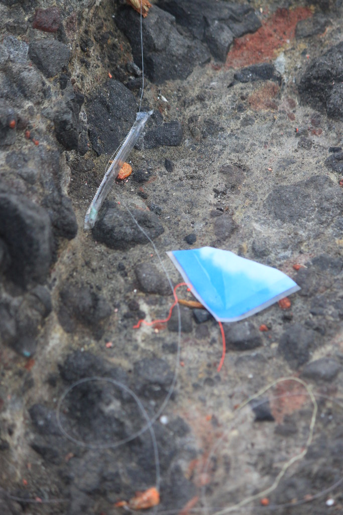 釣魚平台上的人為垃圾（魚線、吸管套、被撕下的塑膠包裝的一角）