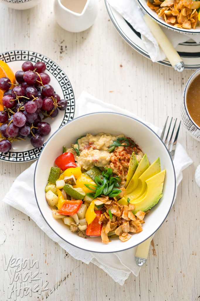 Image of bowl of savory oats with veggies, coconut bacon, and avocado, on a white table top